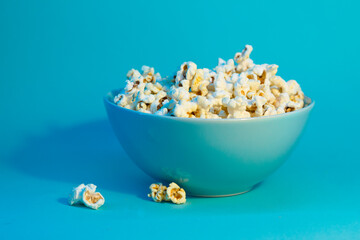 Bright pictures of popcorn. Popcorn in a blue plate. Blue background. Flat lay, copy space. Banner