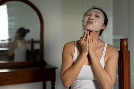 Portraiture of a young asian woman putting on a moisturised face-mask