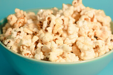Bright pictures of popcorn. Popcorn in a blue plate. Blue background. Flat lay, copy space. Banner