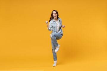 Fototapeta na wymiar Full length of young caucasian overjoyed excited fun student happy woman 20s in denim shirt white t-shirt do winner gesture clench fist celebrating isolated on yellow color background studio portrait