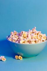 Bright pictures of popcorn. Popcorn in a blue plate. Blue background. Flat lay, copy space. Banner