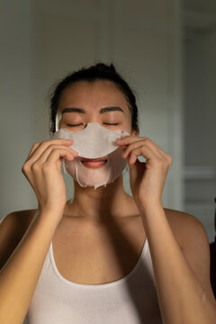 Portraiture of a young asian woman putting on a moisturised face-mask