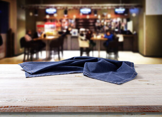 Wooden table with tablecloth, napkin. Cafe background.