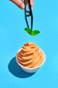 Decoration of caramel cupcake with mint on a blue background.