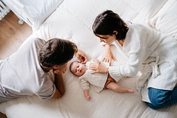 Young parents with baby at bed