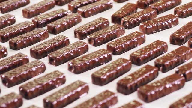 Conveyor transportation of candy bars in chocolate frosting