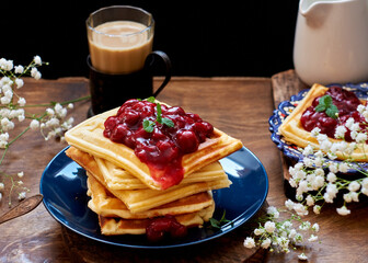 Waffles with cherry jam.  Wooden background, side view