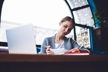 Serious woman entrepreneur working on project in ca cafeteria in daytime