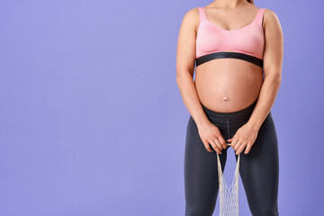 attractive, happy pregnant woman in sportswear holds eco-bag with green apples, Standing on purple background in full-length studio. Healthy, proper nutrition. Vegetarian, dietary food. Vitamins.
