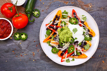 Healthy, plant based bell pepper nachos. Above view table scene on a dark slate background. Low...