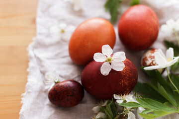 Modern red easter eggs with spring flowers on rustic linen cloth on wooden table. Happy Easter!