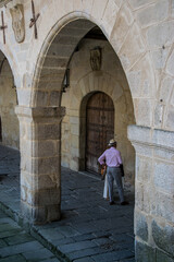 Fototapeta na wymiar Un hombre descansa a la sombra bajo las arcadas de un palacio de piedra del siglo XVI en la localidad de Trujillo, España