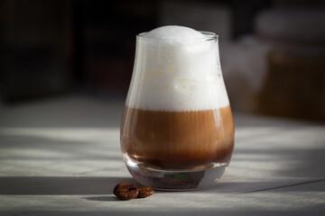 Glass with milky coffee latte or cappuccino in the morning. Sunlight, good day concept.