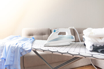 Electric iron and a pile of clothes on an ironing board