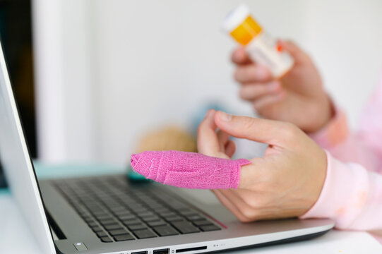 Patient at laptop with bandaged finger checks prescription