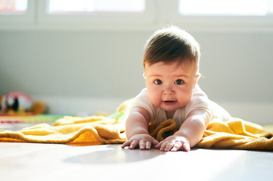 Funny baby lying on blanket on floor