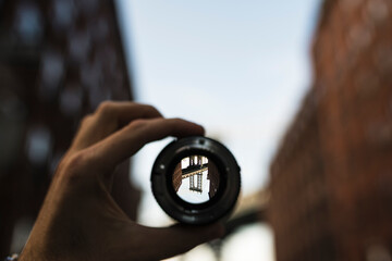 Hand holding a lens against bridge in New York City at sunset