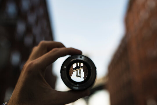 Hand holding a lens against bridge in New York City at sunset