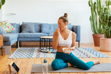 Female athlete eating healthy food and watching video