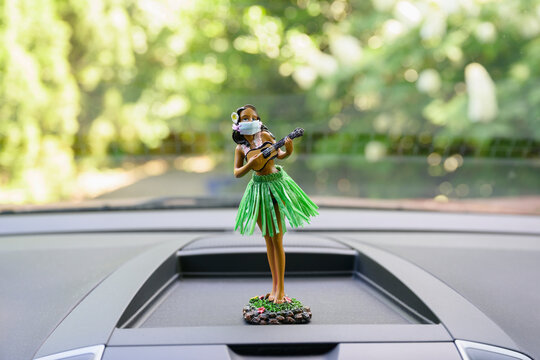Car dashboard hula girl wearing a face mask
