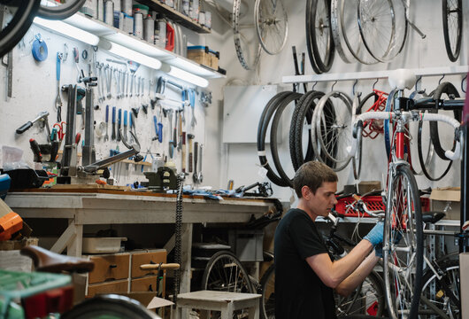 Mechanic Repairing Bicycle In Repair Shop