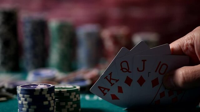 Player revealing Royal Flush cards in hand. Chips, cards and dices on poker table in casino
