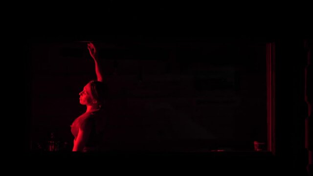 A woman in red light dances an isoteric dance
