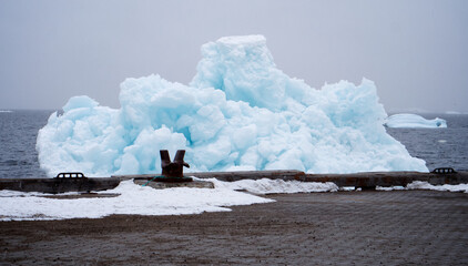 Greenland melting, iceberg at town wharf. Bergs from glaciers cause sea level rise.