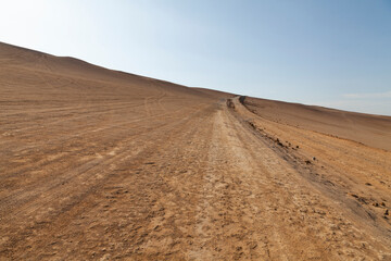 Landscape photograph of dunes and dirt track, in the Paracas desert, on the Lagunillas Route, near Las Minas Beach in the Paracas National Reserve, Pisco, Ica, Peru.