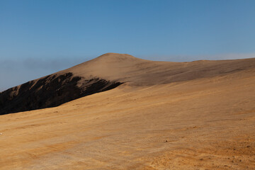 Landscape photography of red dunes and sands, near the cliffs, in the Paracas desert, on the Lagunillas Route, in the direction of Las Minas Beach in the Paracas National Reserve, Pisco, Ica, Peru.