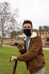 Caucasian man wearing a mask talking on the phone while riding an electric scooter. Palma de Mallorca, Spain