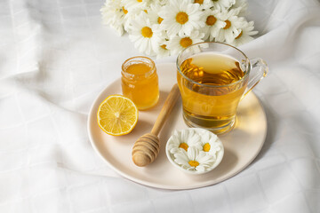 Chamomile flowers and chamomile tea. Chamomile tea in glass teacup with flowers, honey and lemon, top view, prevention of seasona flu colds