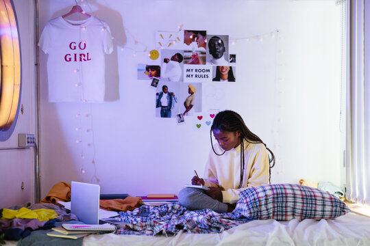 Black teenager making notes on bed