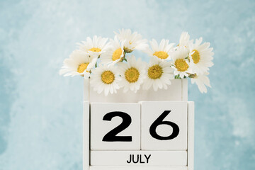 White cube calendar for july decorated with daisy flowers with copy space