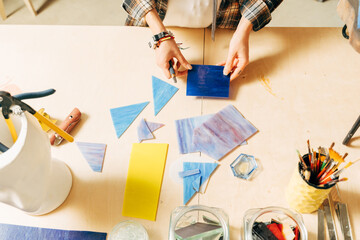 Female hands laying out a mosaic element on the table while making mosaik