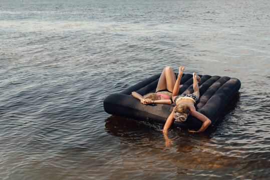 Boy and his mom swim in open water on an inflatable mattress