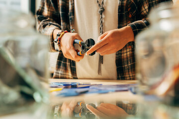 Artist holding tweezers and making mosaic art while spending time at workplace