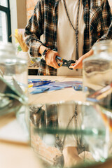 Artist holding mosaic tools and hand crafting, while using tweezers to make mosaic