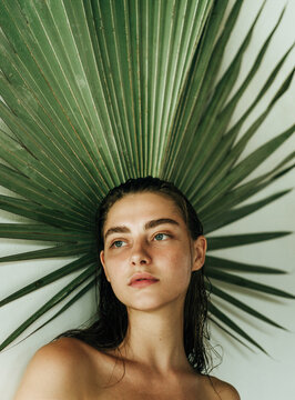 Portrait of a beautiful girl on a background of palm leaf