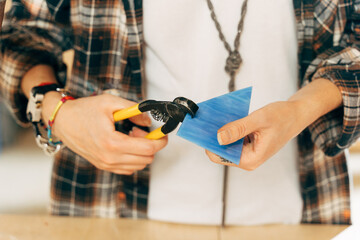 Woman artist holding blue glass and cutting it with special tools