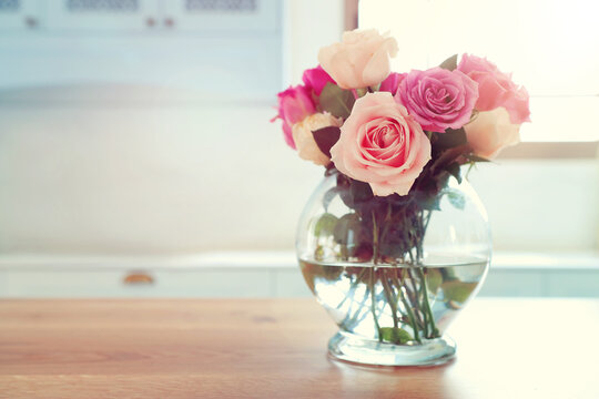 spring bouquet of pastel pink roses over wooden table at home interior