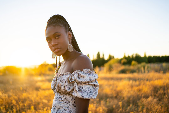 Black Woman With Braids On A Field At Sunset In Summer.