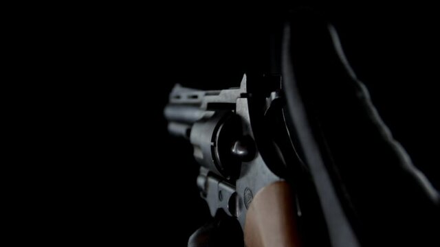 Hand of man shooting gun on black background. Criminal with gun and leather gloves.