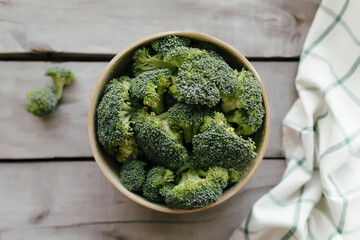 Green fresh broccoli in bowl on wooden background. Healthy eating concept