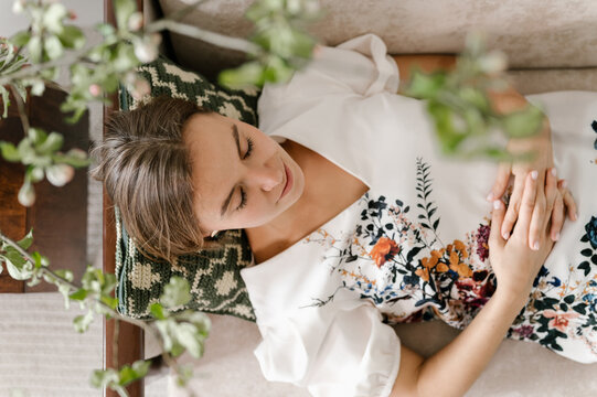 Young woman in embroidered dress resting on sofa