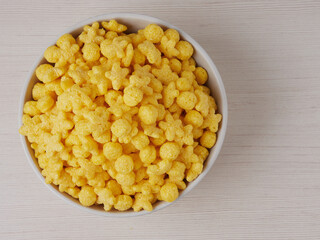 Tasty corn flakes in bowl with bottle of milk. Rustic wooden background with homespun napkin. Healthy crispy breakfast snack. Place for text. Top view, flat lay.