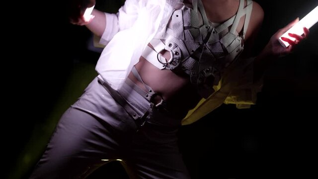 sexy female go-go dancer is illuminating her body and face by led lamps in hands