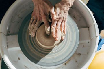 Potter’s hand correcting during shaping clay blank on a potter's wheel