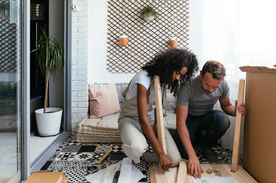 Young multiethnic couple installing furniture together