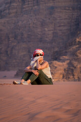 Woman sitting on a desert dune at sunset